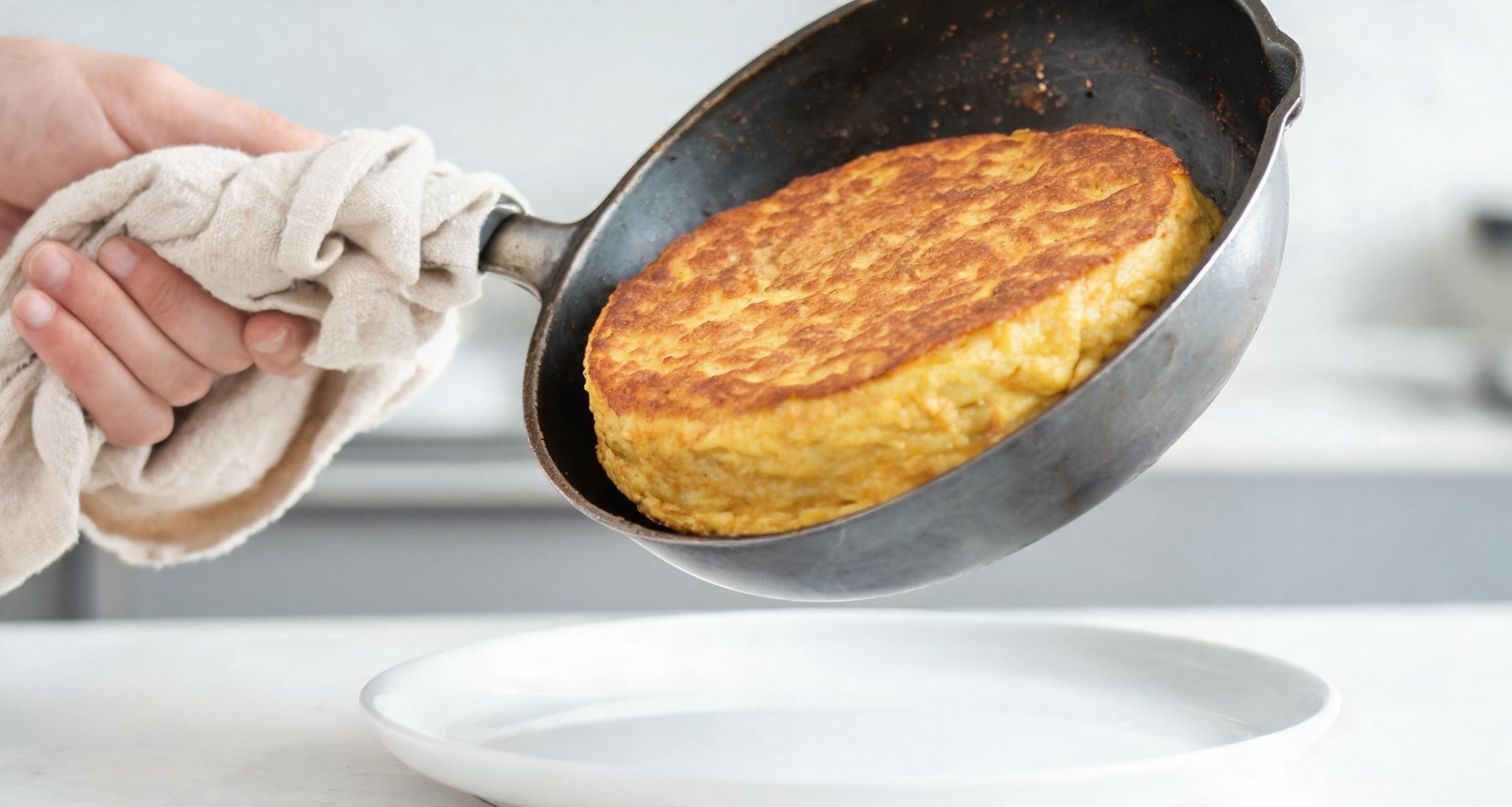 Flipping a Spanish tortilla onto a plate to cook the other side